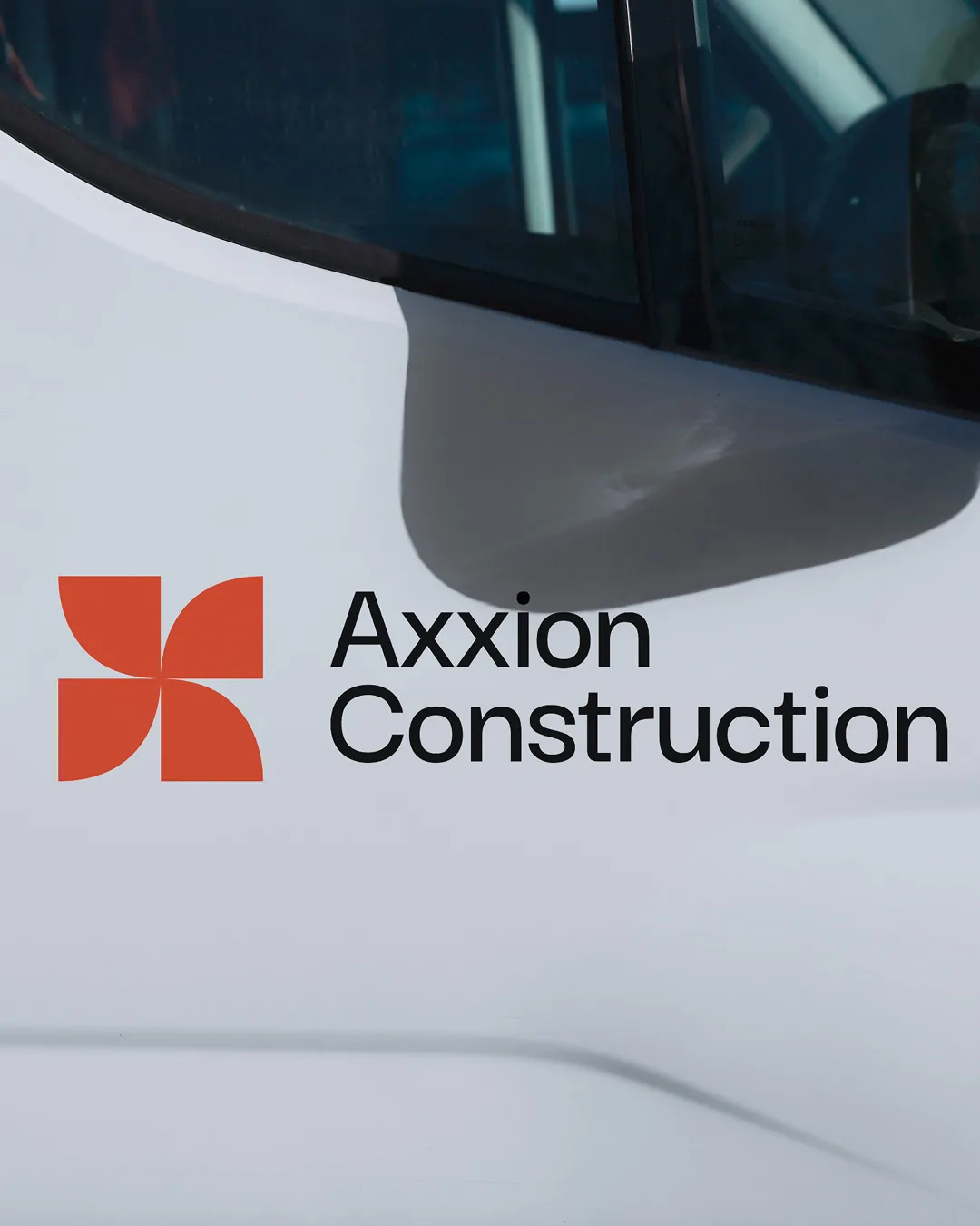 Le logo Axxion Construction sur la portière blanche d’une camionnette.