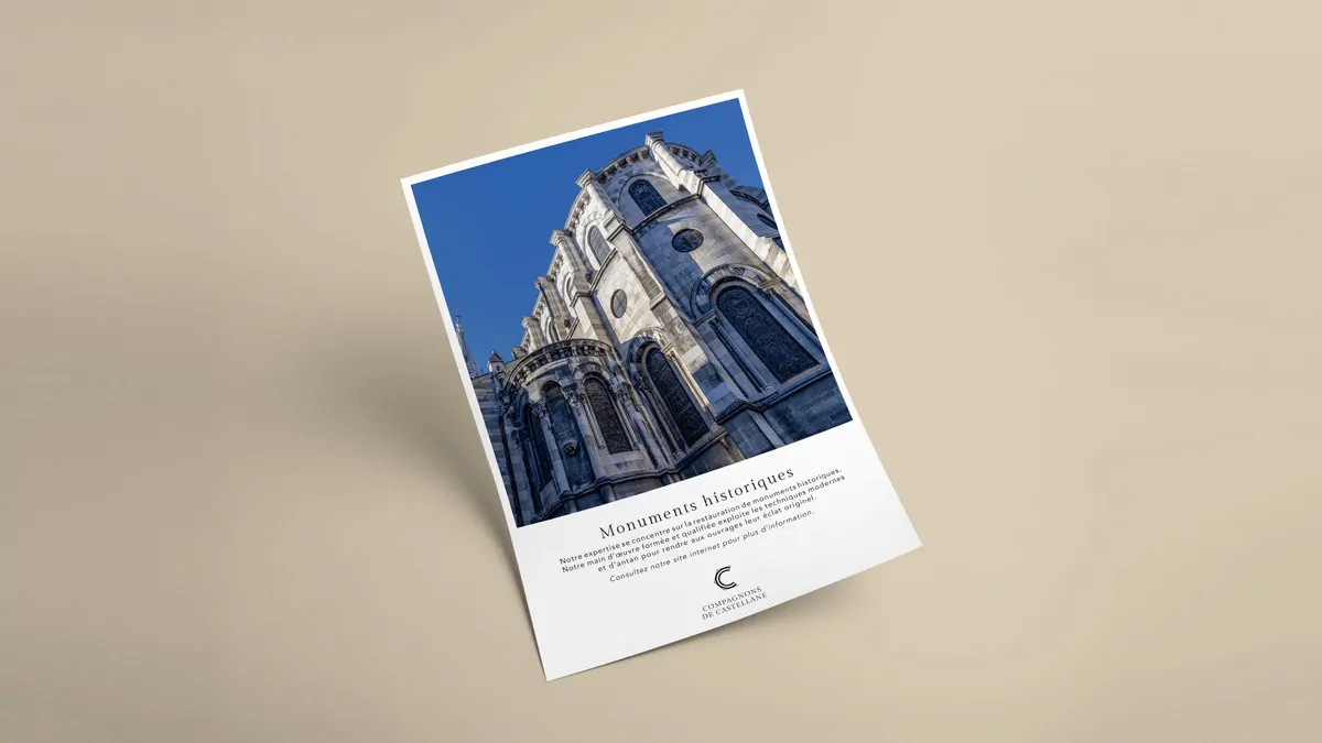 Une fiche « Monuments historiques » posée en biais sur un fond beige : la photo d’un clocher de pierre.