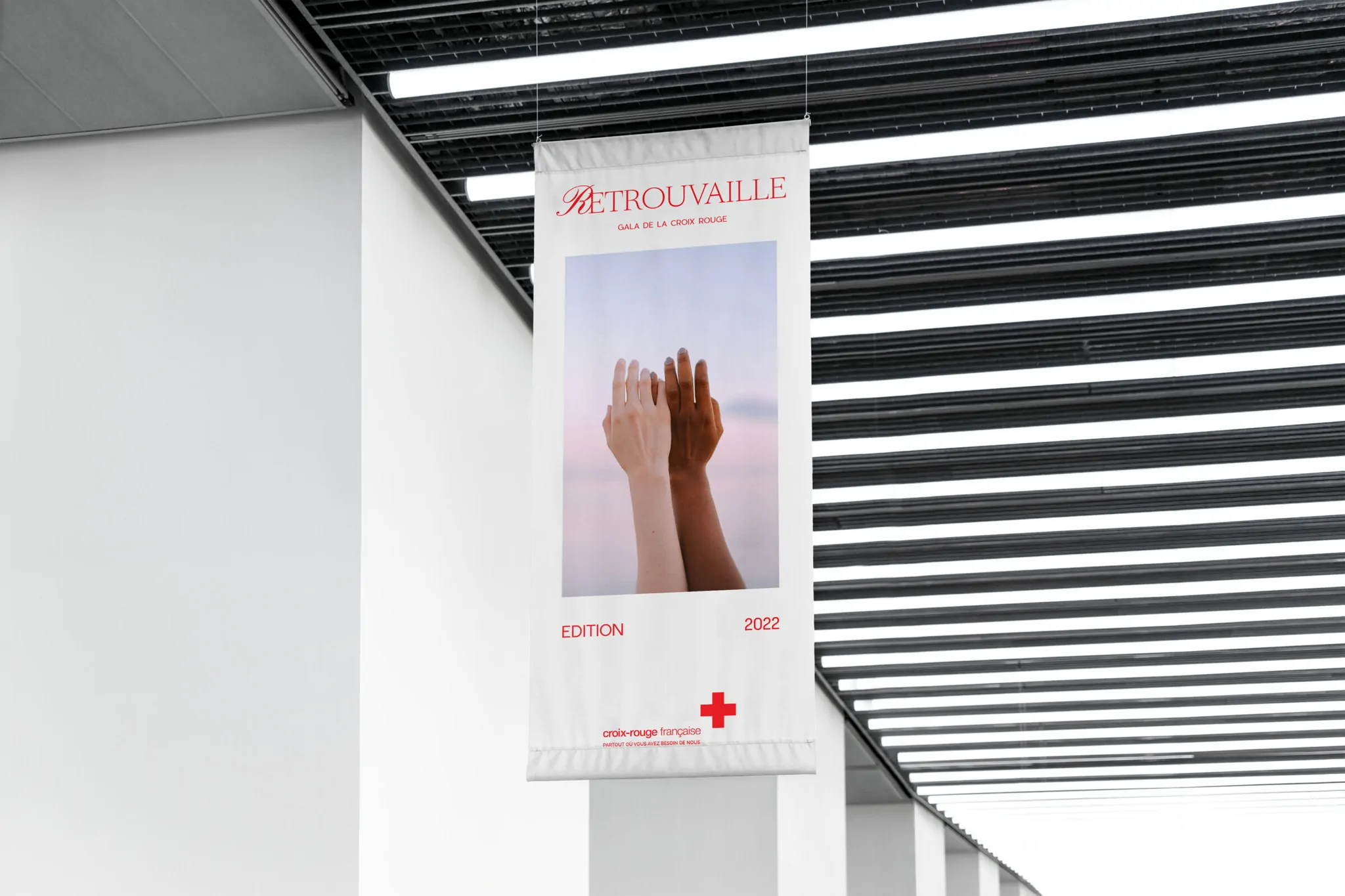 Une bannière suspendue sous un plafond à lames : « Retrouvailles » et la photo de deux mains.