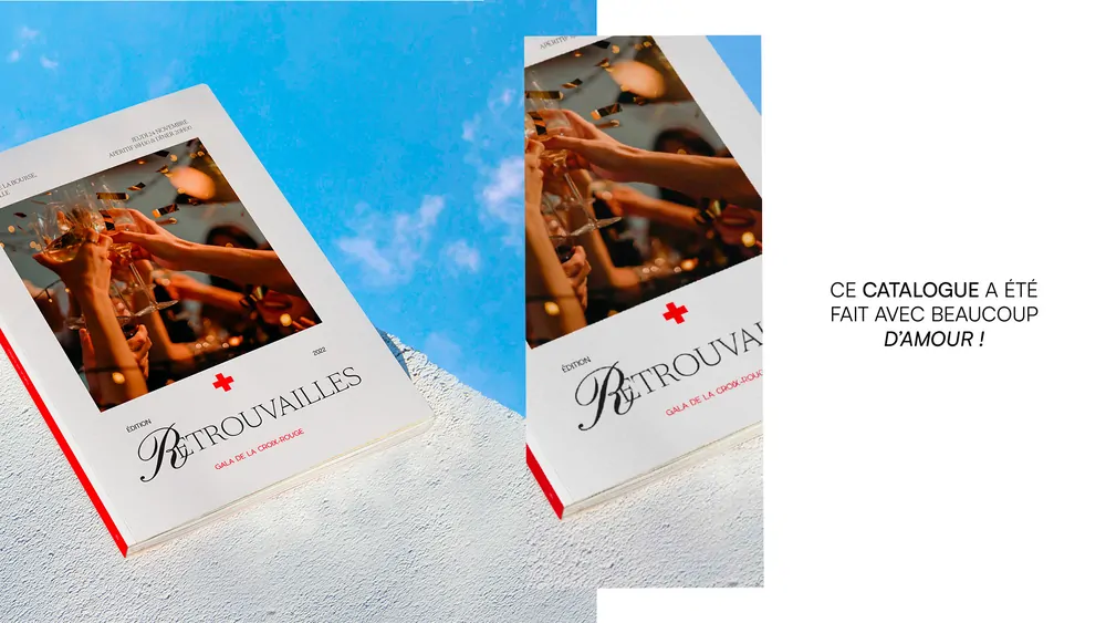 Le catalogue du gala, une couverture blanche à bandeau rouge, posé sur un ciel bleu, avec la mention « Ce catalogue a été fait avec beaucoup d’amour ! ».