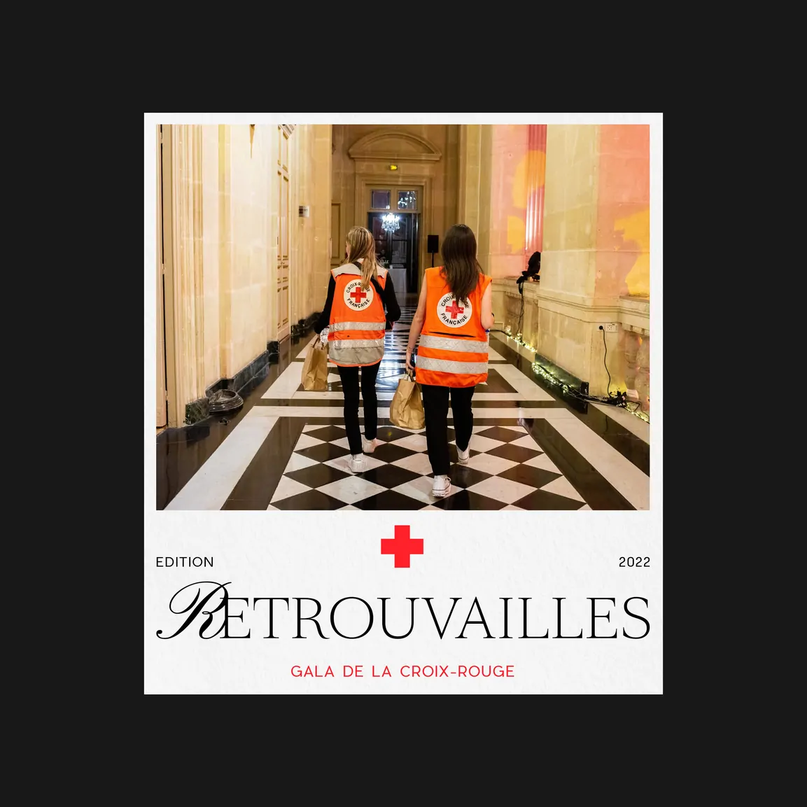 Deux bénévoles en gilets orange traversent un couloir au sol en damier noir et blanc.