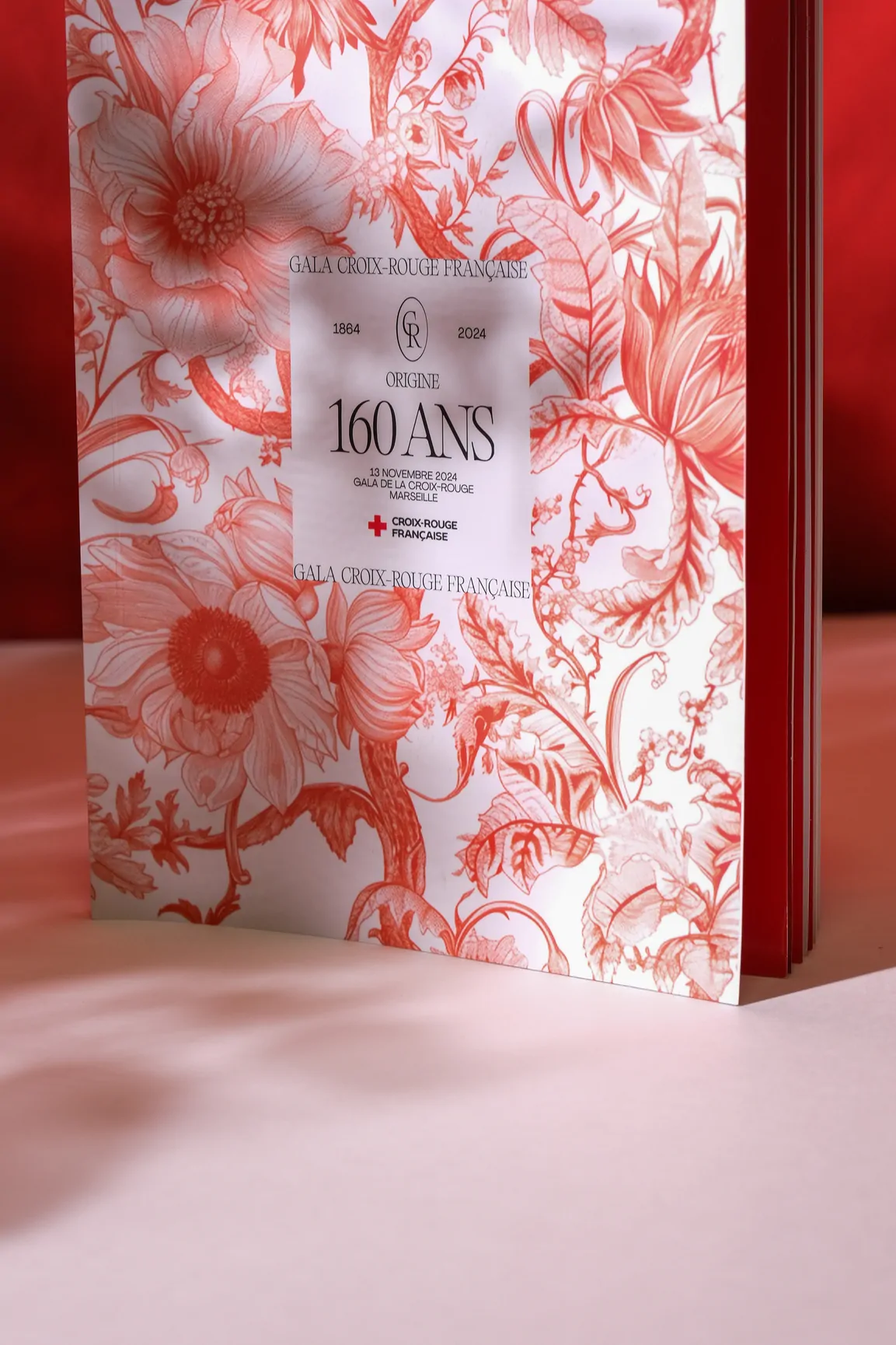 La couverture du catalogue, en gros plan : le motif floral rouge et blanc et le cartouche « Origine 160 ans ».