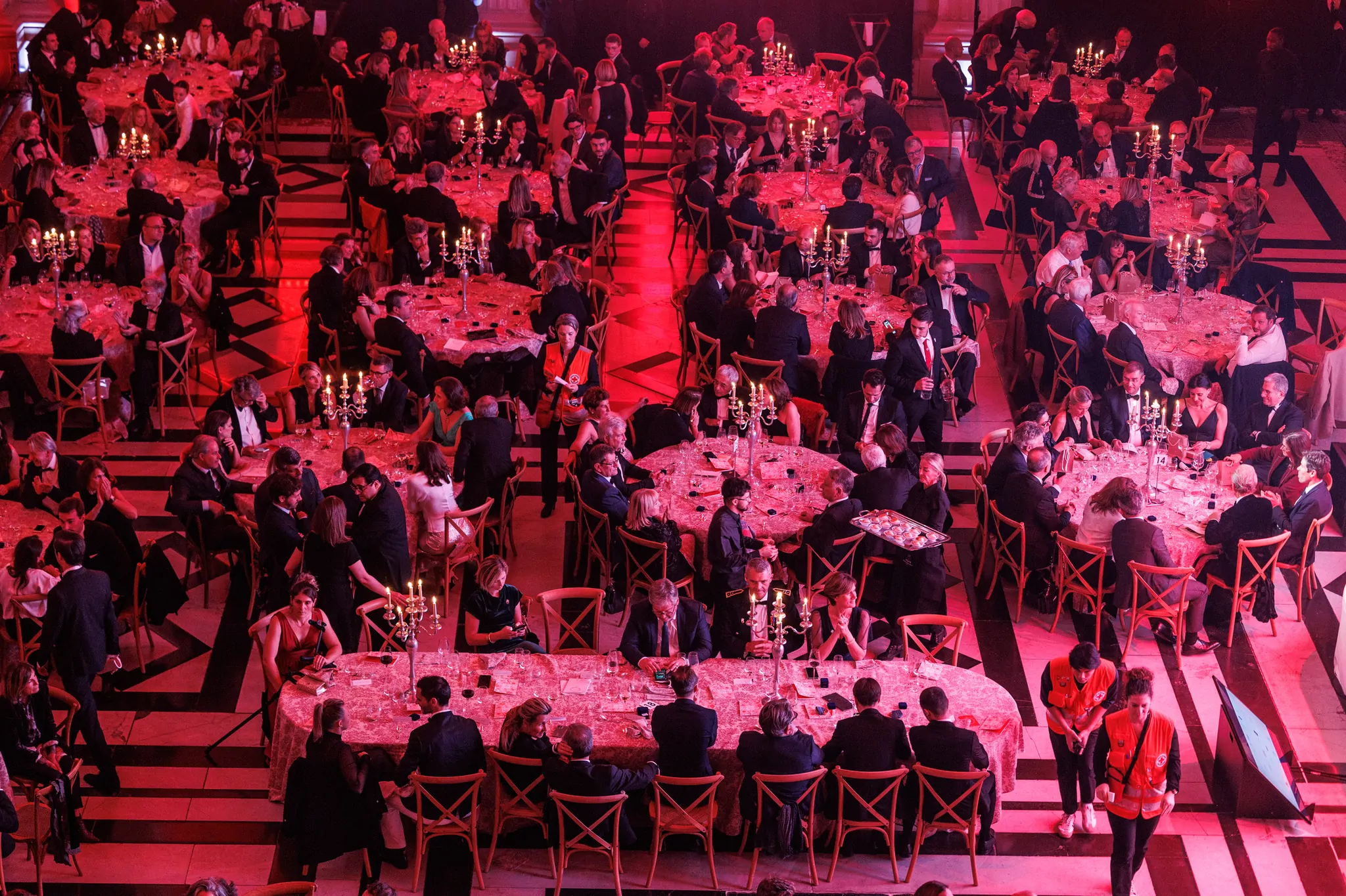 La salle du Palais de la Bourse vue d’en haut : les tables rondes des convives baignées de lumière rouge.