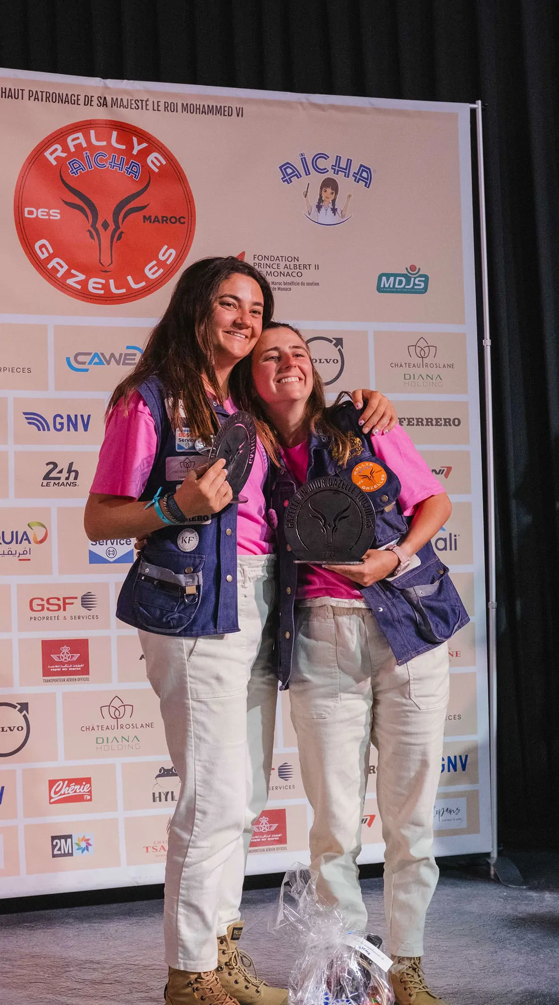 Marie et Olivia s’enlacent devant le panneau du Rallye Aïcha des Gazelles, lors de la remise des prix.
