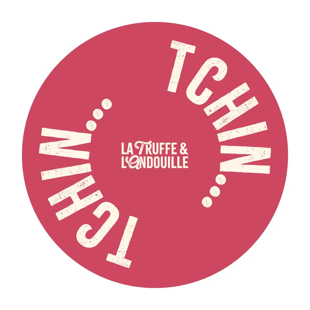 Un sticker rond rose, le mot « Tchin » courbé autour du logotype.