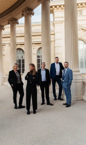 Cinq membres de l’équipe de PCC debout sous une colonnade du Palais Longchamp.