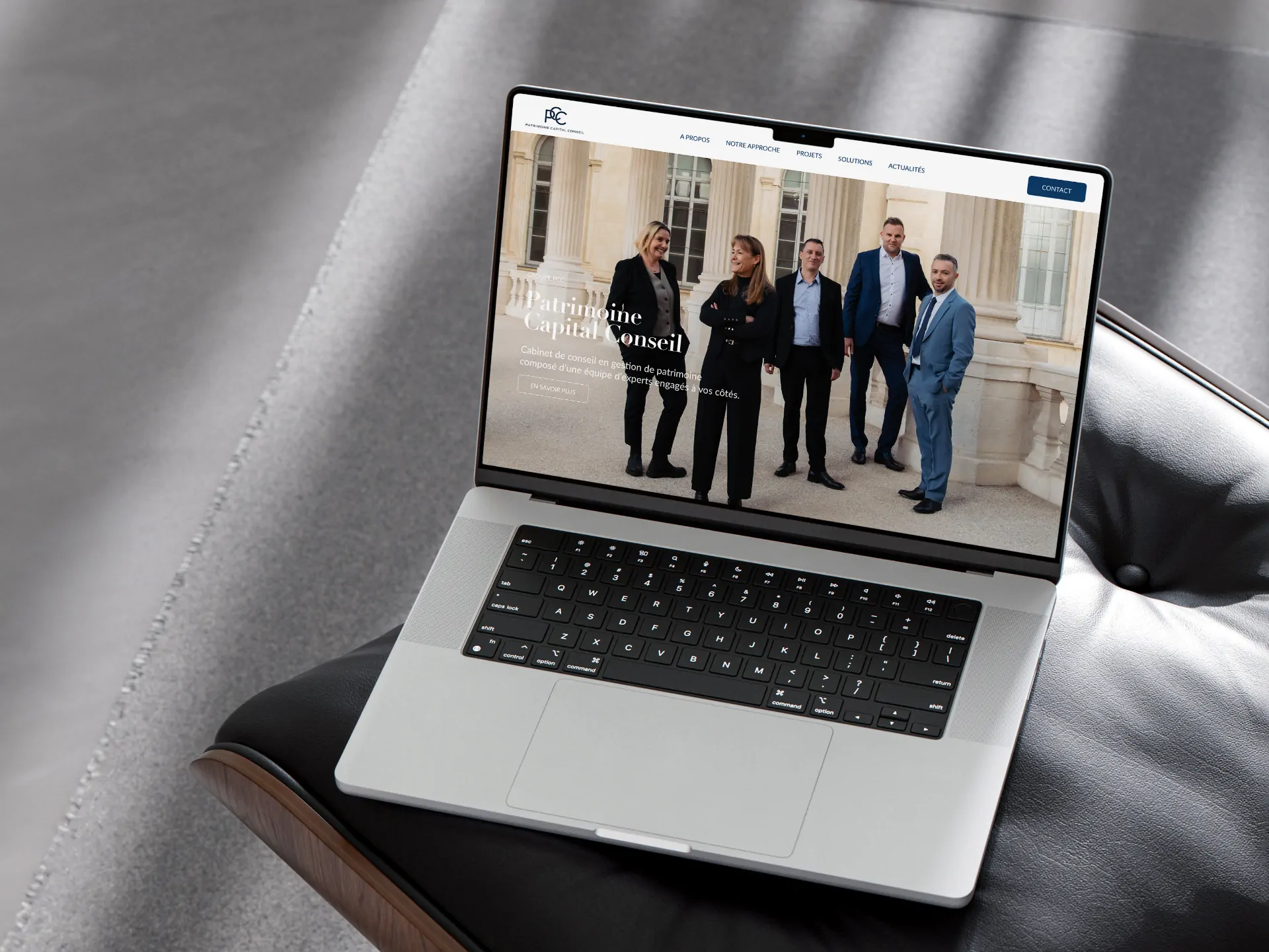 Un ordinateur portable posé sur un fauteuil de cuir noir, affichant le site de PCC : l’équipe devant la façade du palais.