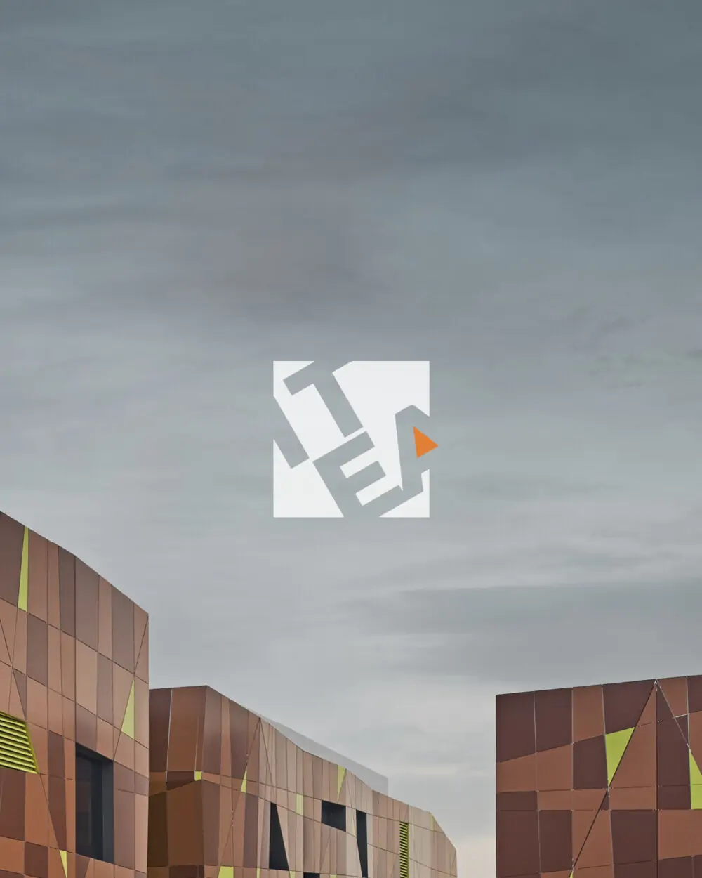 ITEA — le logo en blanc sur une façade de bardage couleur rouille, sous un ciel gris