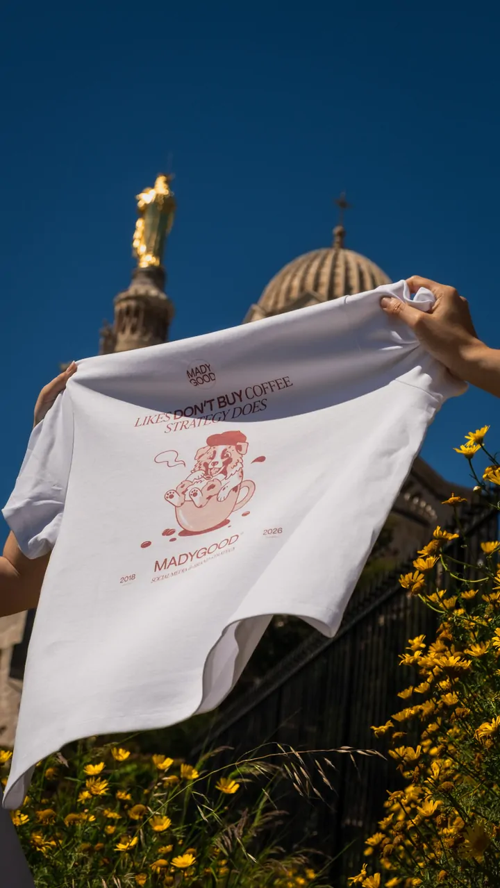Un tee-shirt tenu à bout de bras devant un ciel bleu profond, la Bonne Mère dorée et le dôme de Notre-Dame de la Garde derrière.